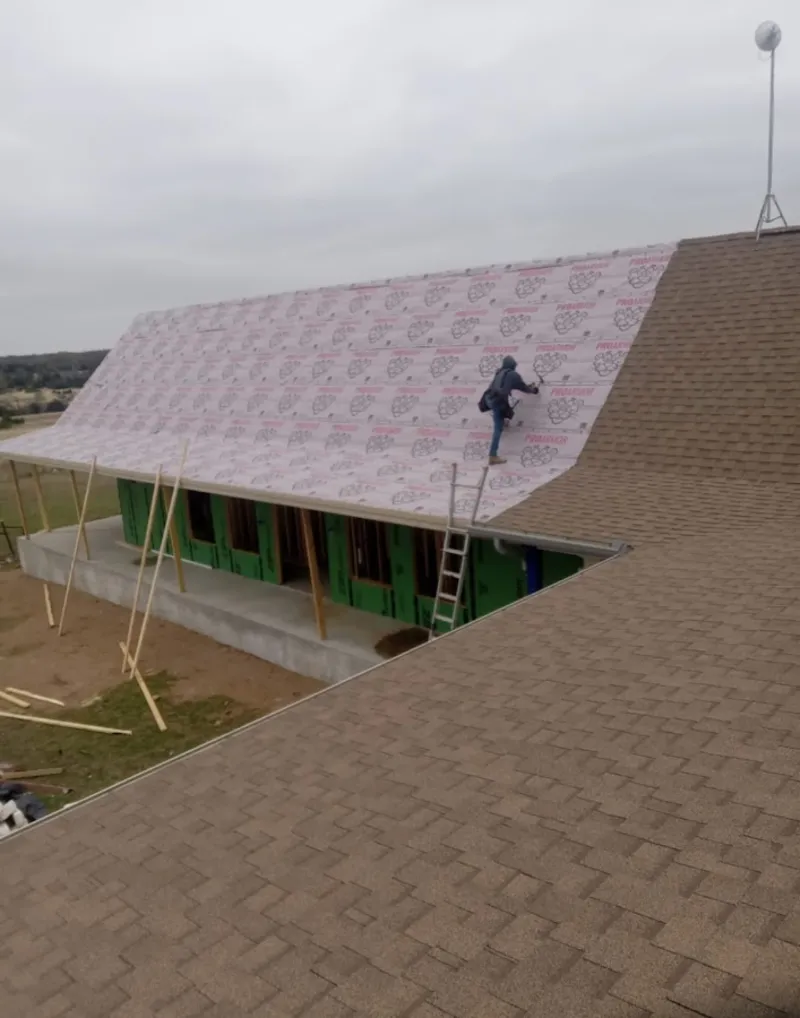 Worker preparing underlayment for a metal roof installation in Hyattsville